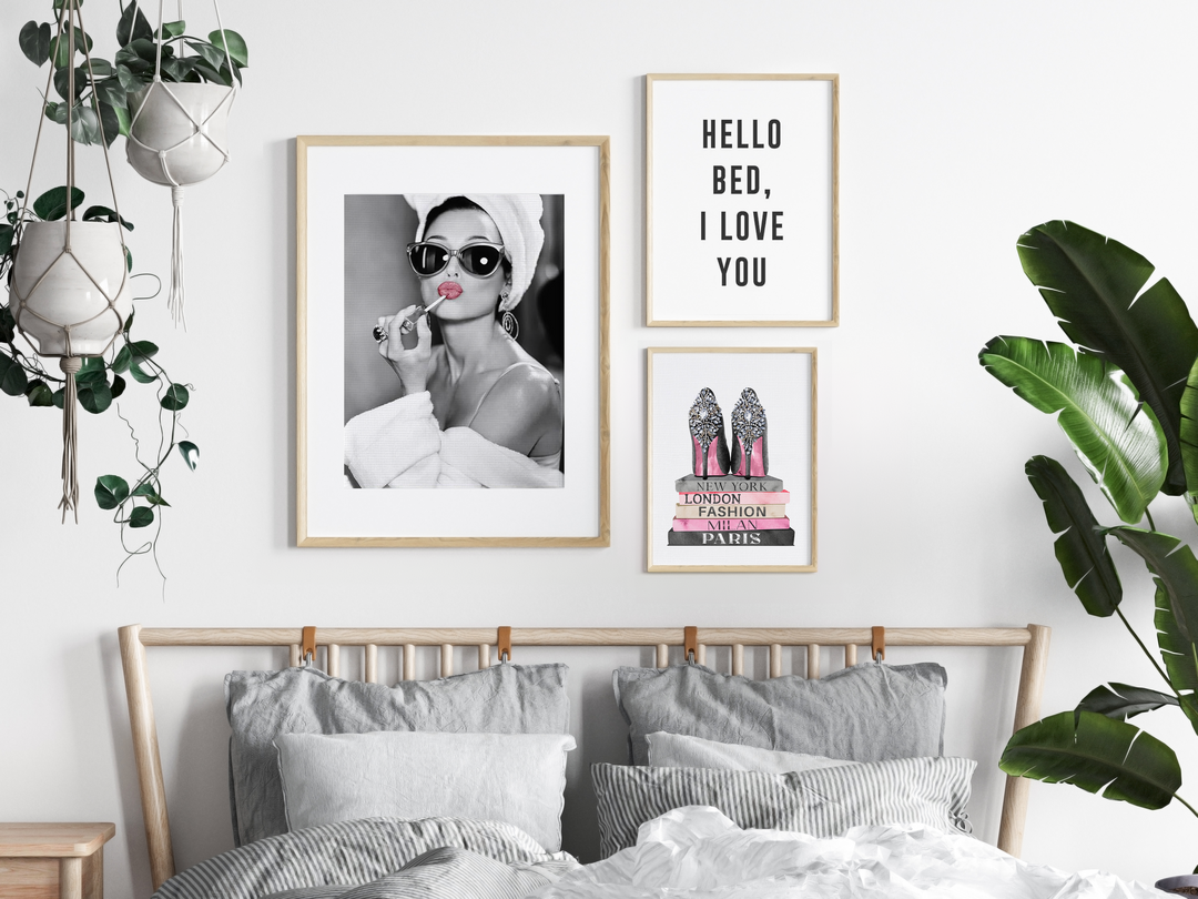 Bed with three framed prints above it and a hanging plant and floor plant