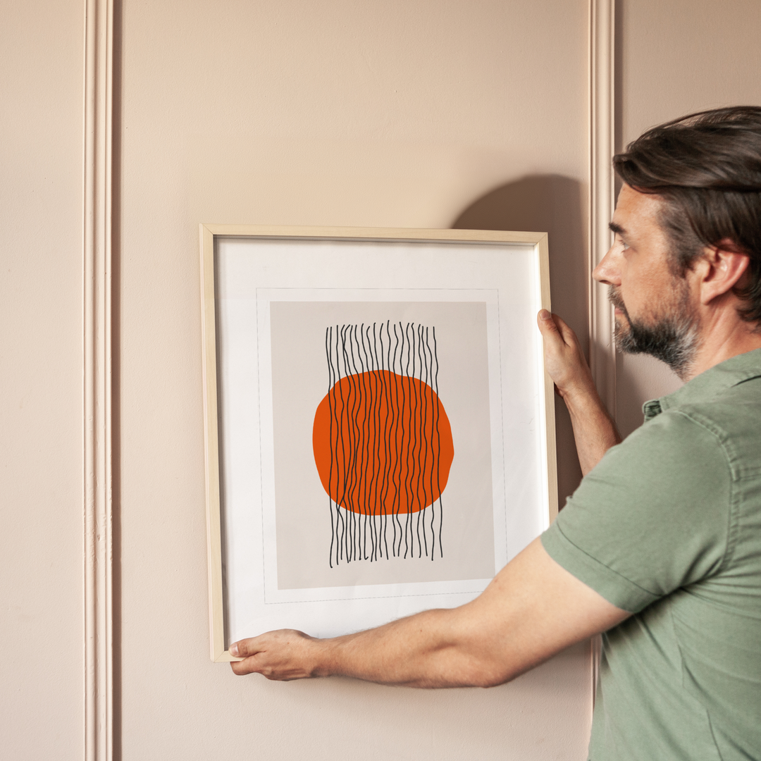 Middle aged man in green shirt holding up abstract wall decor